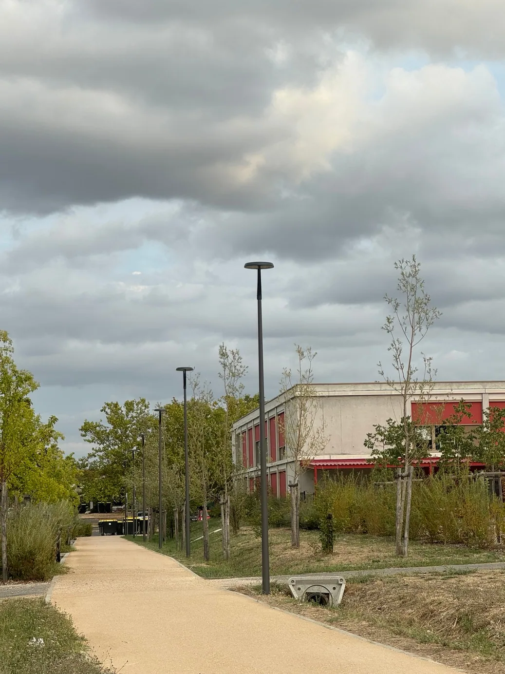 Cheminement piétonnier de Saint-Loup-Cammas bordé de mâts d'éclairage LED devant un bâtiment communal — réalisation MIDI LUM
